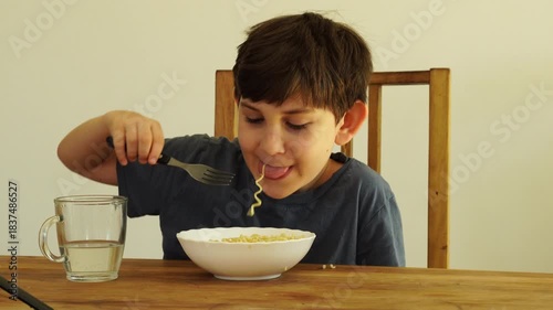 Boy eats noodles at the kitchen