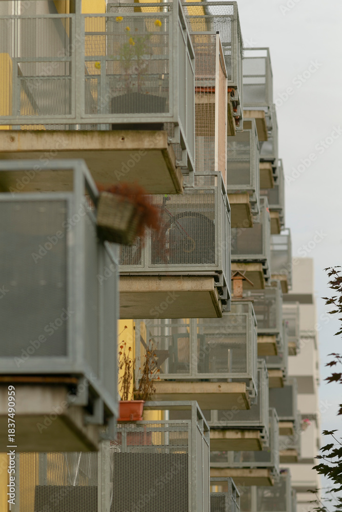 Fototapeta premium Contemporary balcony series, Urban residential facade featuring repeated balcony design, Series of modern balconies on apartment building facade showcasing geometric repetition and evening warmth
