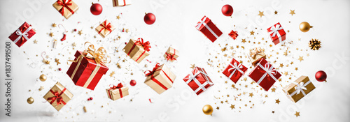 falling red and gold christmas gift boxes with shiny baubles and golden stars scattered loosely with confetti and ribbons in a chaotic arrangement