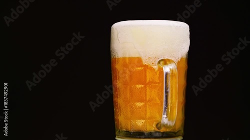 A glass of beer is sitting on a table. The glass is half full and the foam is still visible. Concept of relaxation and enjoyment, as the beer is a popular beverage for unwinding and socializing
