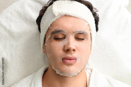 Cuadro en lienzo Young man with facial sheet mask in beauty salon, top view