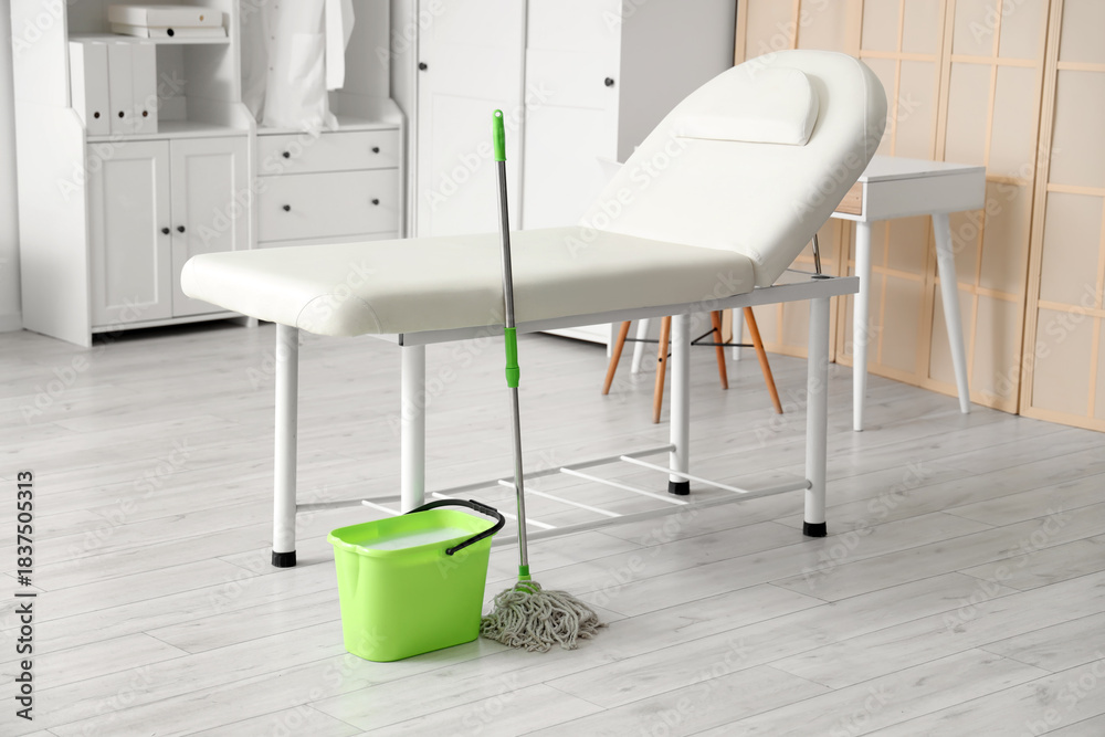 Fototapeta premium Green bucket with mop near couch in medical office
