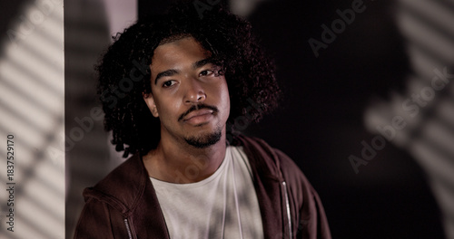Studio shot of a handsome African American man with curly hair posing in studio lighting. This image is suitable for fashion beauty and editorial content.