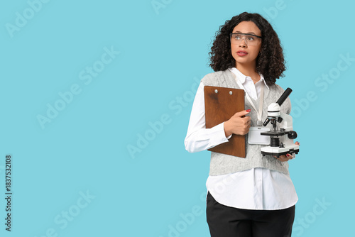 Female African-American teacher with microscope and clipboard on blue background