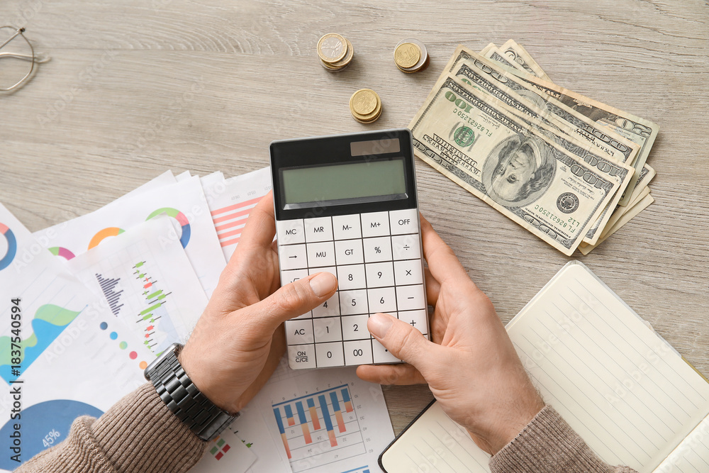 Fototapeta premium Male hands with calculator counting money at table in office. Top view