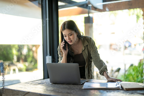 Young asian woman working remotely, talking on phone
