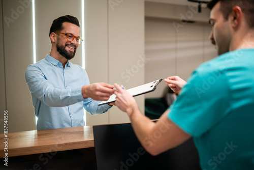 Foto Patient signing medical form at clinic reception