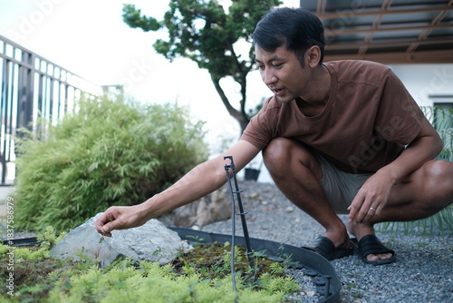A man is kneeling down and touching a plant