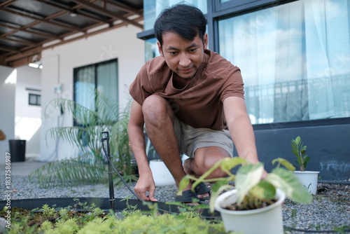 A man is kneeling down to water a plant