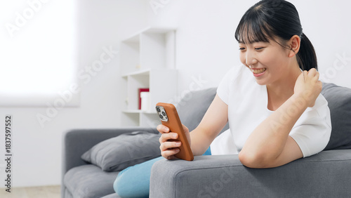 リビングでスマホを使う10代女性