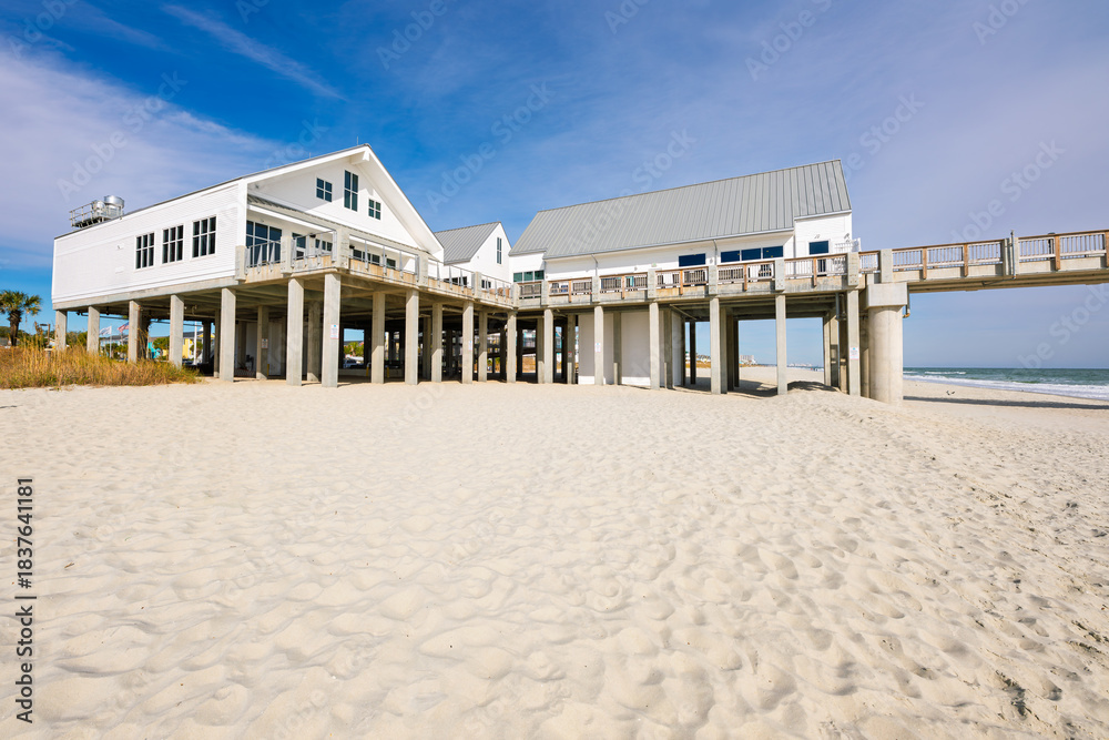 Naklejka premium View from the sandy beach of the Grand Strand along the Atlantic Ocean of the Surfside Beach Pier, with Myrtle Beach in the distance, in Surfside Beach, South Carolina.