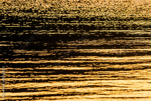 Close up of the golden ripples on the surface of water at sunset