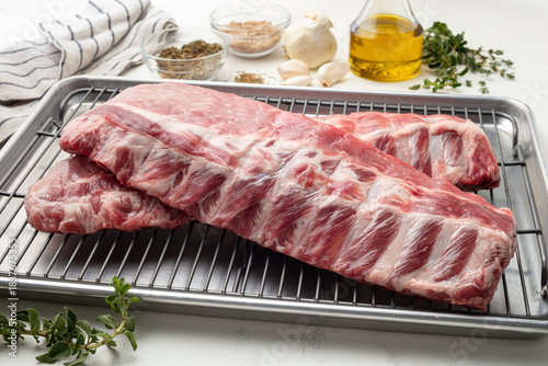 Tablou pe pânză Medium shot of raw rib steak on a metal rack with prop ingredients in the background