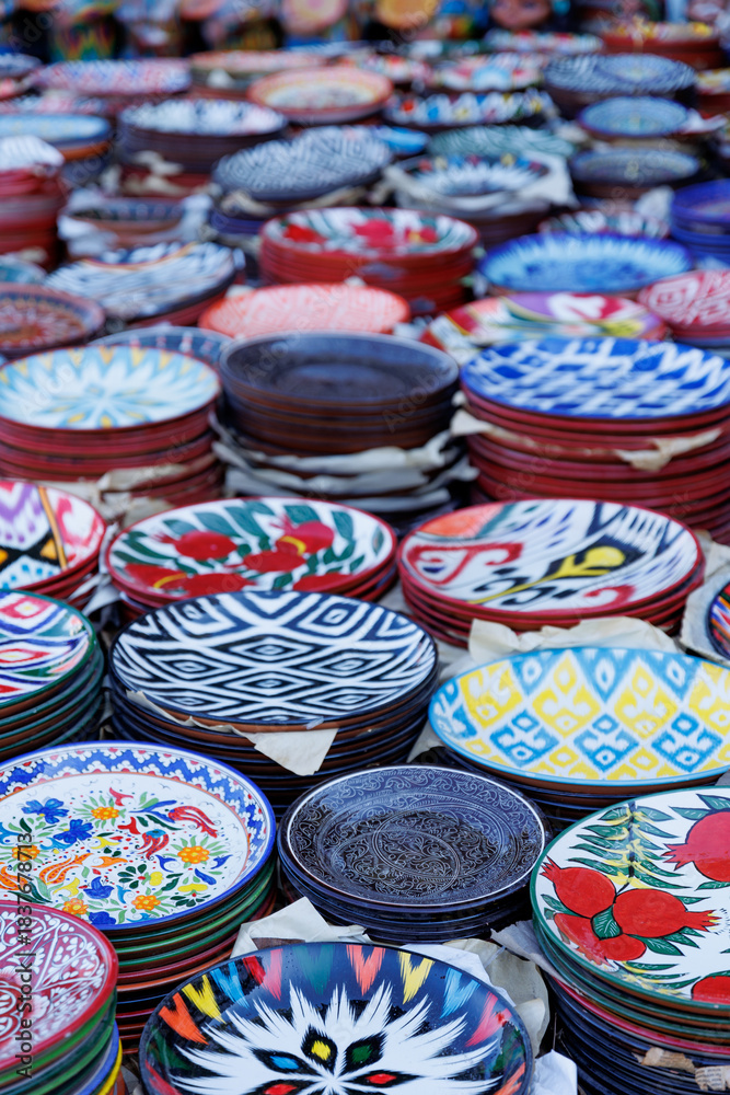 Fototapeta premium October 30, 2025 Tashkent, Uzbekistan. a vibrant collection of hand-painted ceramic plates, each boasting intricate folk patterns