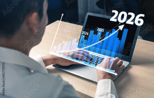 Foto A business professional is engaged in data analysis on a laptop, showcasing projections for growth from 2022 to 2026