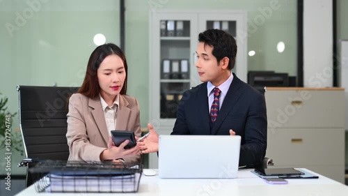 Two business workers talking on the smartphone and using laptop at the office.