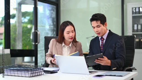 Two business workers talking on the smartphone and using laptop at the office.