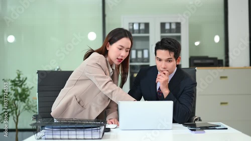 Two business workers talking on the smartphone and using laptop at the office.