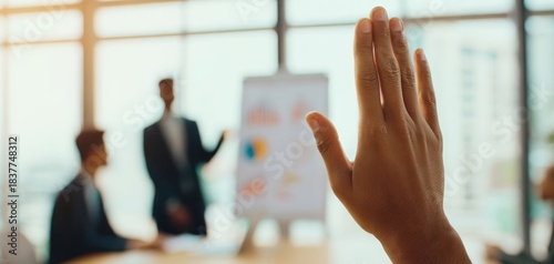 The raised hand in a business meeting asking a question during presentation