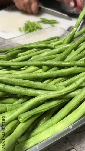 Hand movement of a bean cutter with a sharp knife on a white chopping board