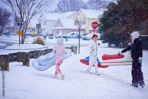 Group of Friends, Children Enjoying Winter Sledding Fun on Inflatable Sleds in a Snowy Suburban Neighborhood. Active Winter Playtime