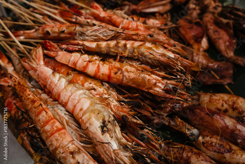 Freshly caught shrimps cooked on the grill. Seafood on skewers at the Asian market.