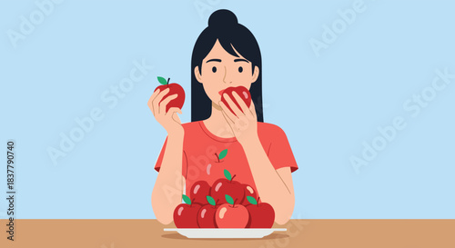 A healthy young woman is eating a crisp red apple with a large plate of fresh apples in front of her for a healthy snack.