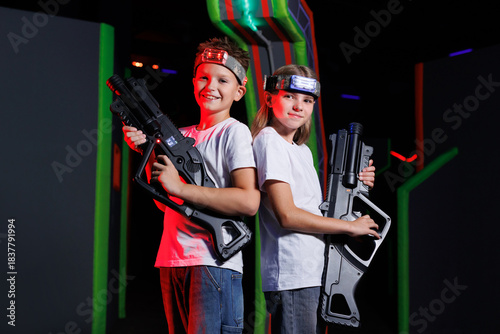 Boy and girl holding laser guns and wearing headbands. Laser tag game.