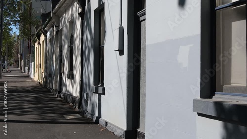 Quiet inner suburban street with old house facades and long sidewalk shaded by trees in West Melbourne, Australia. Concept of old homes, heritage architecture, and urban living