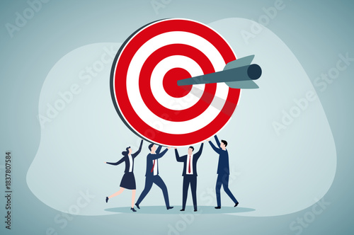 Four professionals collectively hold a large target, with an arrow hitting its bullseye, symbolizing team collaboration to achieve shared goals.