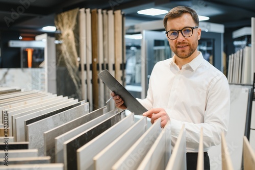 Shop assistant showing ceramic tiles to customer in store