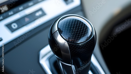 A modern, sleek automotive gear shifter knob, featuring a high-tech carbon fiber design with polished metallic accents, presents a sophisticated aesthetic.
