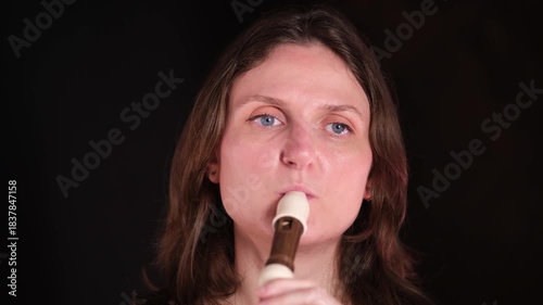 Woman playing a recorder wind musical instrument. Female musician performing classical music. Closeup portrait for creative art and hobby.