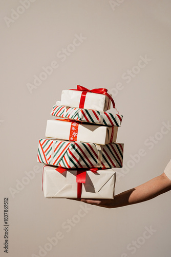 Caucasian hand holding a tall pile of wrapped Christmas presents