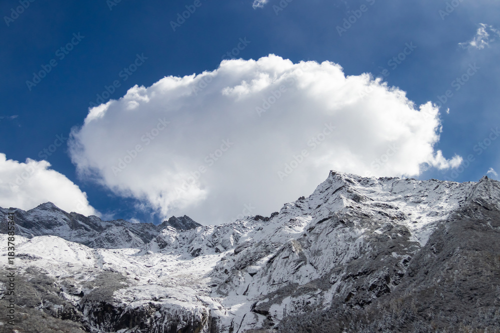 Fototapeta premium Snowy mountain landscape with dramatic cloud and bright sky capturing calm mood at Bipenggou, China.