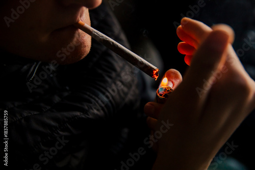 Close-up of a man lighting a marijuana cigarette with a lighter