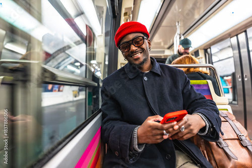 Slika na platnu Young man smiling using phone while commuting by subway