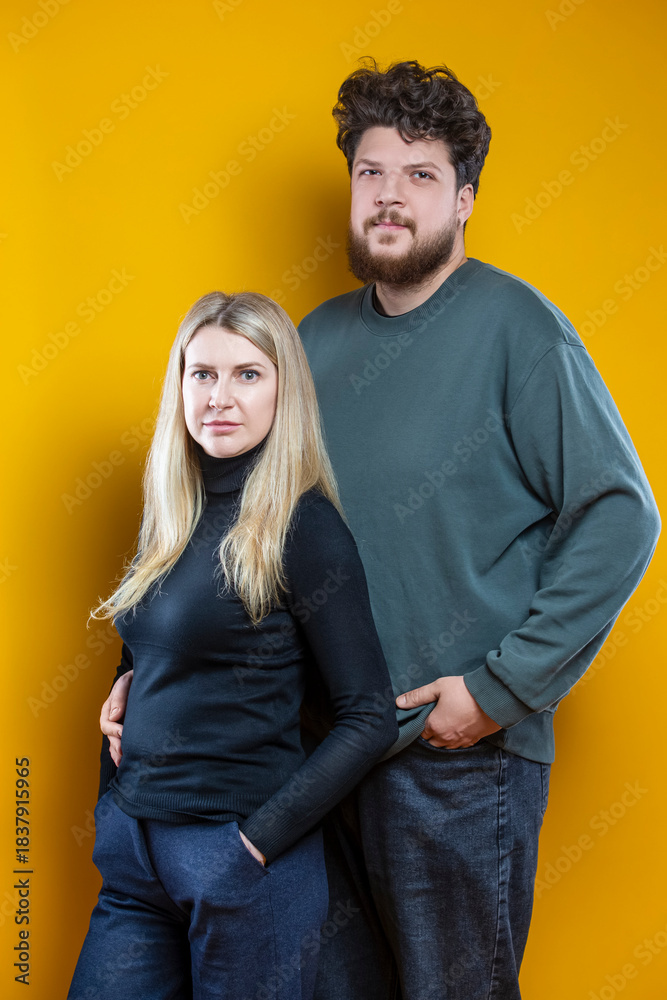 Obraz premium Lifestyle Concepts. Young Caucasian Smiling Happy Adorable Couple As Friendly Family Man And Woman Casual Clothing Together Embracing Cuddle Isolated on Seamless Yellow