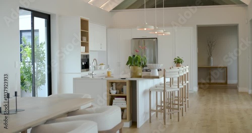 Camera is panning right revealing island, stools and dining table by sliding doors to show layout