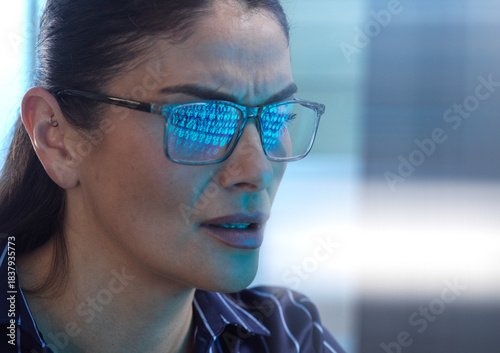 Woman looking at computer screen during cyber attack with binary code reflection