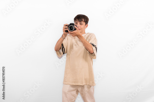 young photographer casual dressed Generation Z white male model fun teenage boy photo with DSLR camera. happy smile expressing joy in positive entertaining way in plain background studio setting