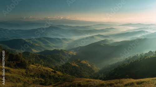misty mountain range at sunrise with layers of green hills and valleys