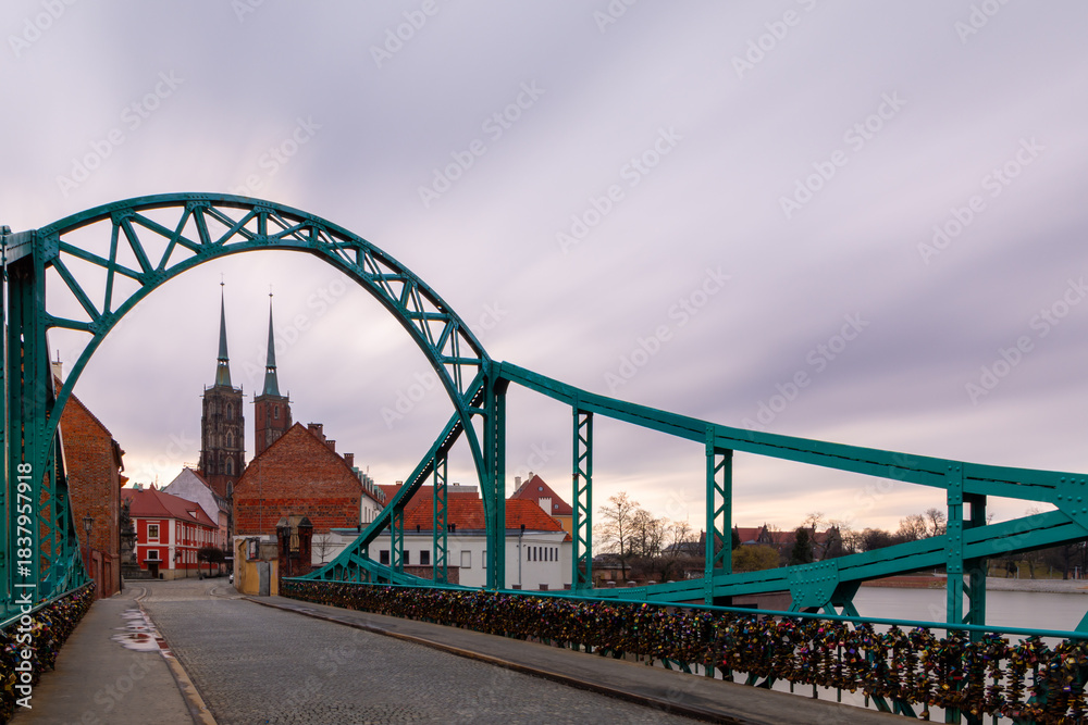 Obraz premium Green Steel Bridge With Love Locks And Cathedral Towers, City River Architecture Landmark Oldtown Travel Walkway. Copy Space