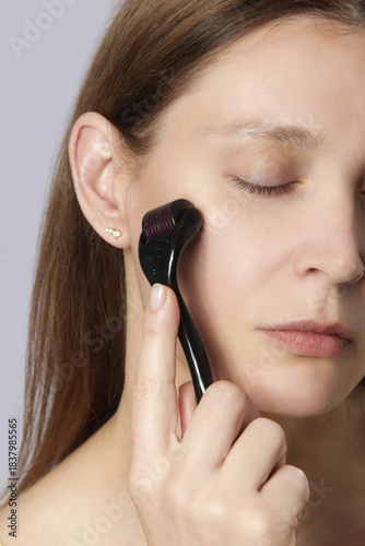 Facial massage with microneedle dermaroller for the treatment of scars, wrinkles and for facial rejuvenation. Simple and cheap skin care at home	