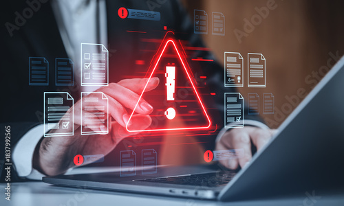 Tableau sur toile Cybersecurity warning concept with hacker alert symbol and digital data breach icons over businessman's hand working on laptop in office background