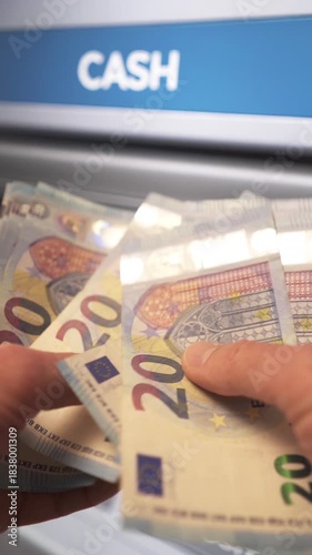 A businessman counts euros after withdrawing cash from an ATM. Banking services, cash withdrawals