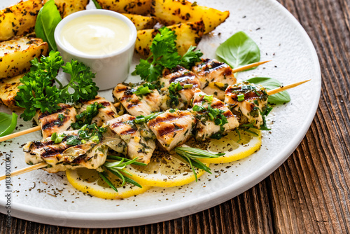 Greek style chicken skewers souvlaki with baked potatoes on wooden background

