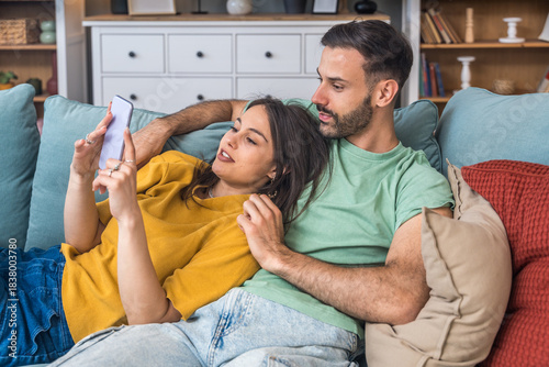 Slika na platnu Couple relaxes together, taking a selfie on a smartphone, laughing at messages,