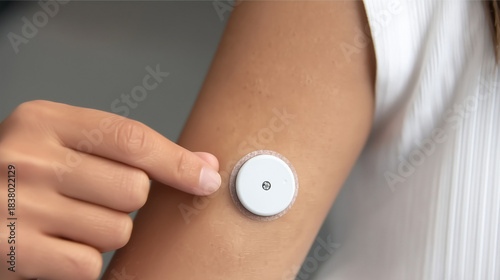 Person's arm wearing a continuous glucose monitor sensor, indicating modern diabetes management, blood sugar monitoring, and health technology for daily care with copy space