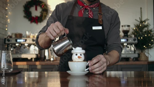 Man barista making festive snowman latte art for Christmas holiday season. Crafting special coffee drink for winter concept.